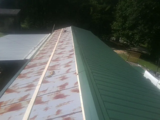 Old rusted panels beside newly installed green metal roofing — Wind Damage Roof Repair by Roofing Brothers in North Creek