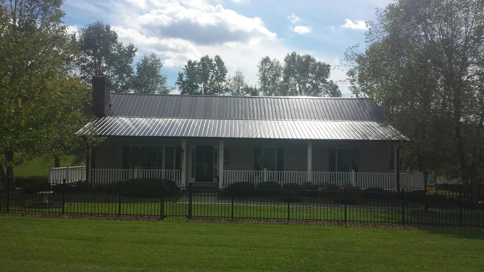 Gray metal roof on a brick ranch with a full width front porch — Gutter Guard Installation work by our crew in North Creek