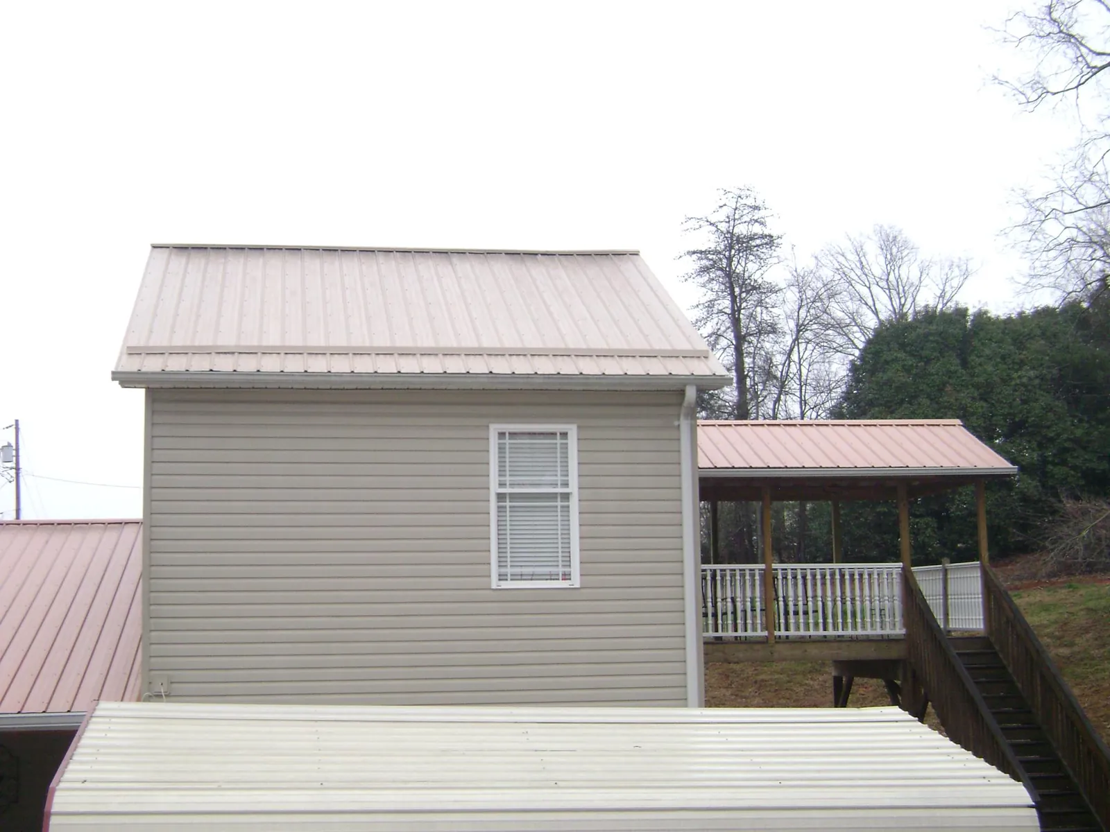 Tan metal roofs on a two story addition and attached porch, from a Roof Replacement job in North Creek