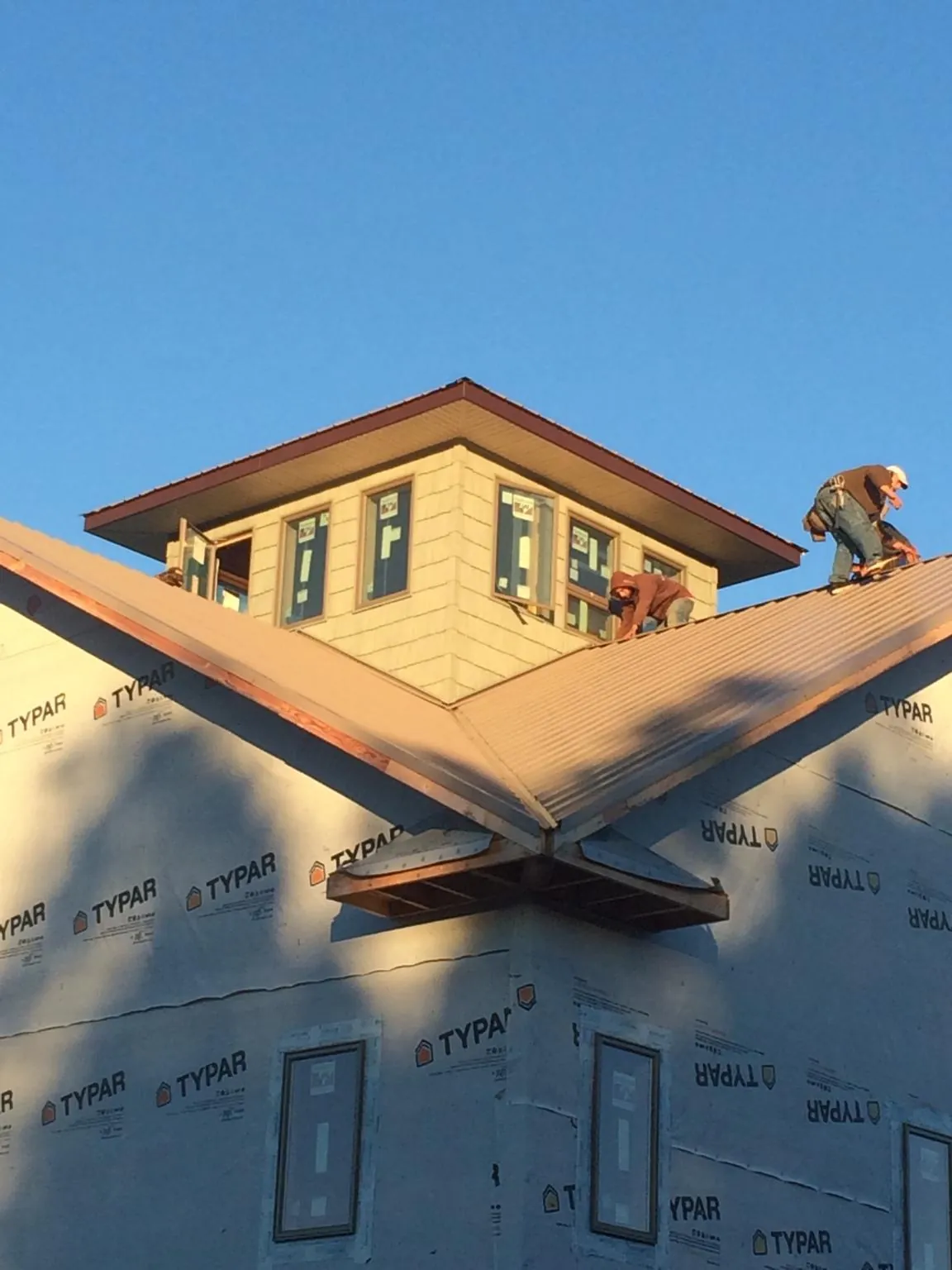 Roofers working around a rooftop cupola on a new metal roof at sunset — Roof Waterproofing in North Creek by Roofing Brothers